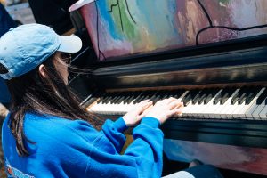 A student playing a colorfully painted piano