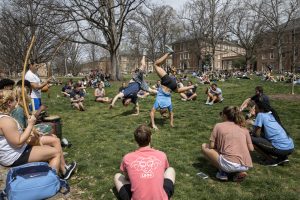 Two students are in the handstand position. They are surrounded by more students sitting in a circle around them.
