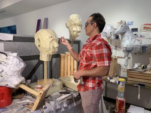 Paul Estrada works on his paper mache sculpture