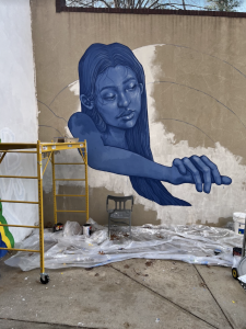 A blue woman painted on the wall with scaffolding in the foreground