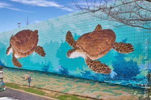 painted on the wall are two brown sea turtles in an ocean of blues and greens