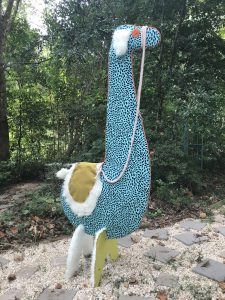a blue polka dot llama sculpture in the woods