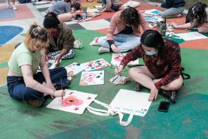 Students paint totes on the basketball court outside Morrison Art Studio
