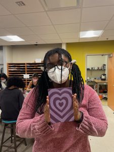 A student holds up a painting of a heart