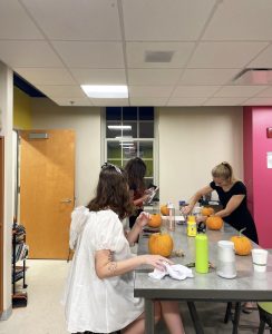 People dressed up for Halloween painting pumpkins